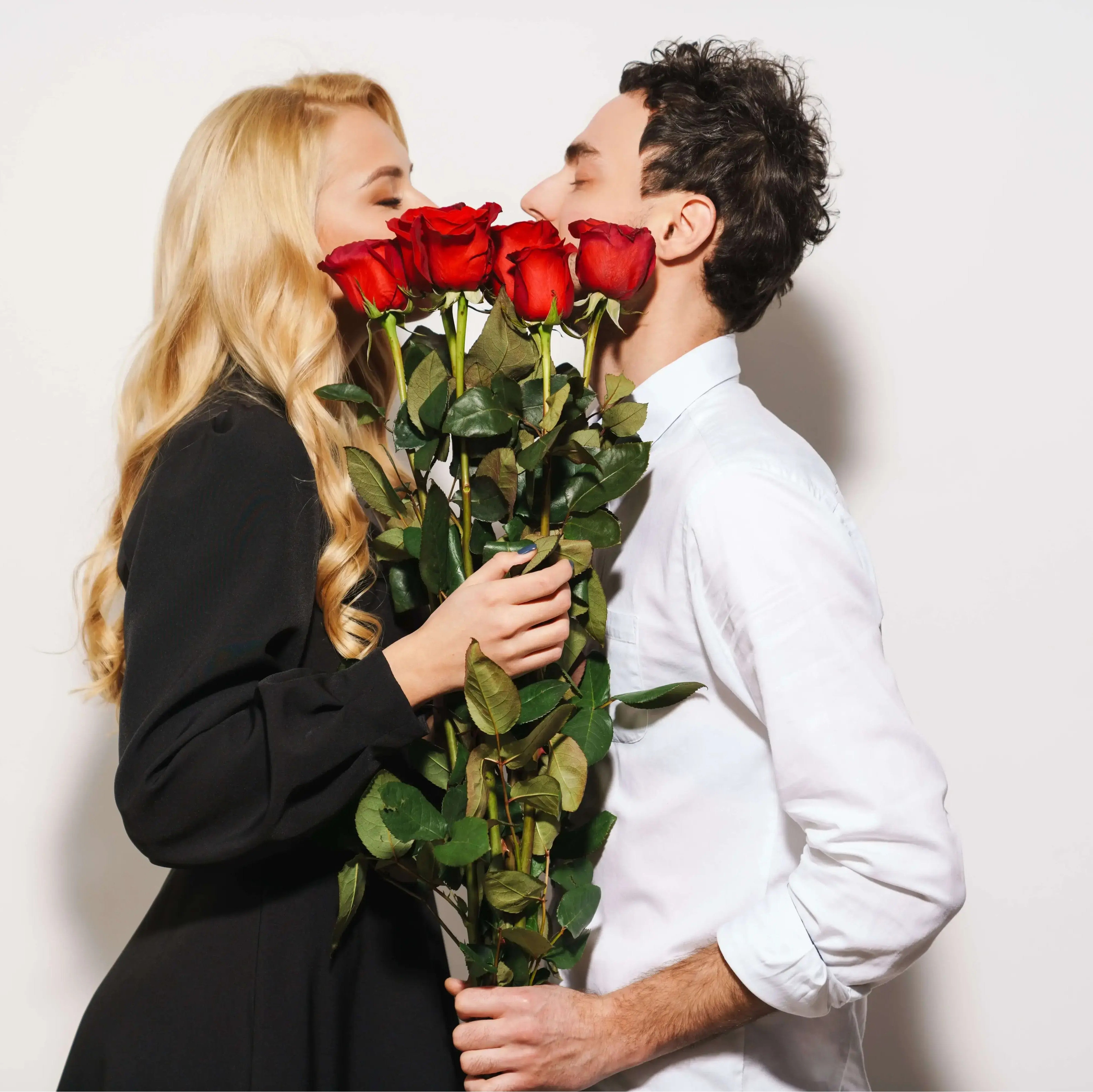 Couple kissing behind red roses