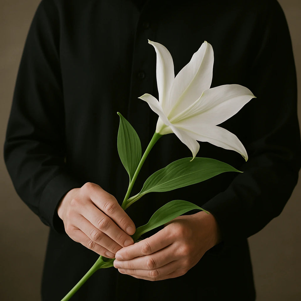 Person holding a white lily, a funeral flower.