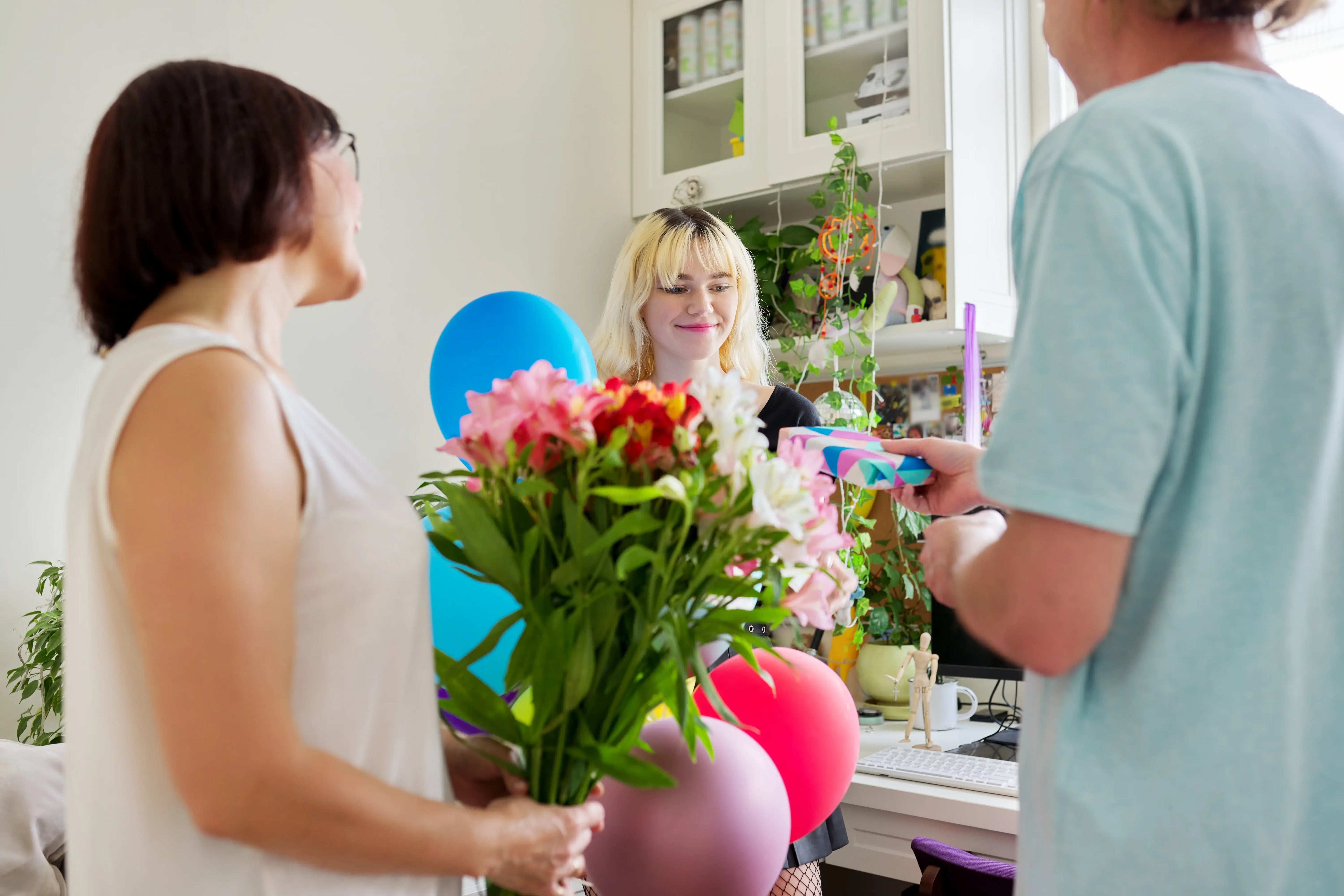 Birthday flowers and balloons being given to woman.