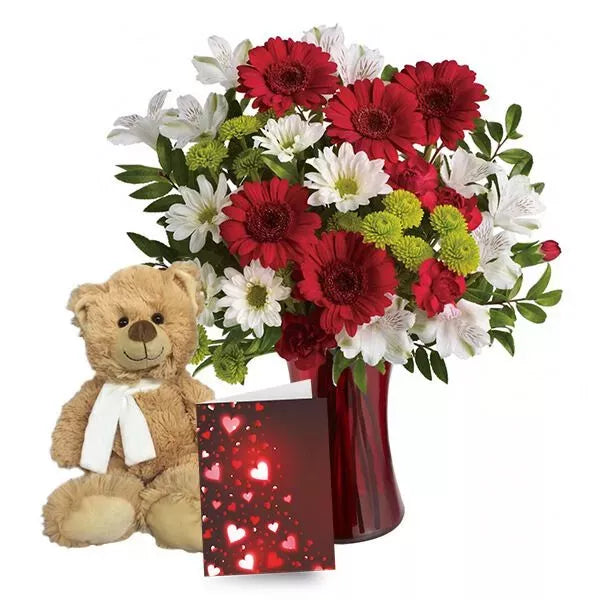 A teddy bear alongside a vibrant bouquet in a red vase with a love-themed card.