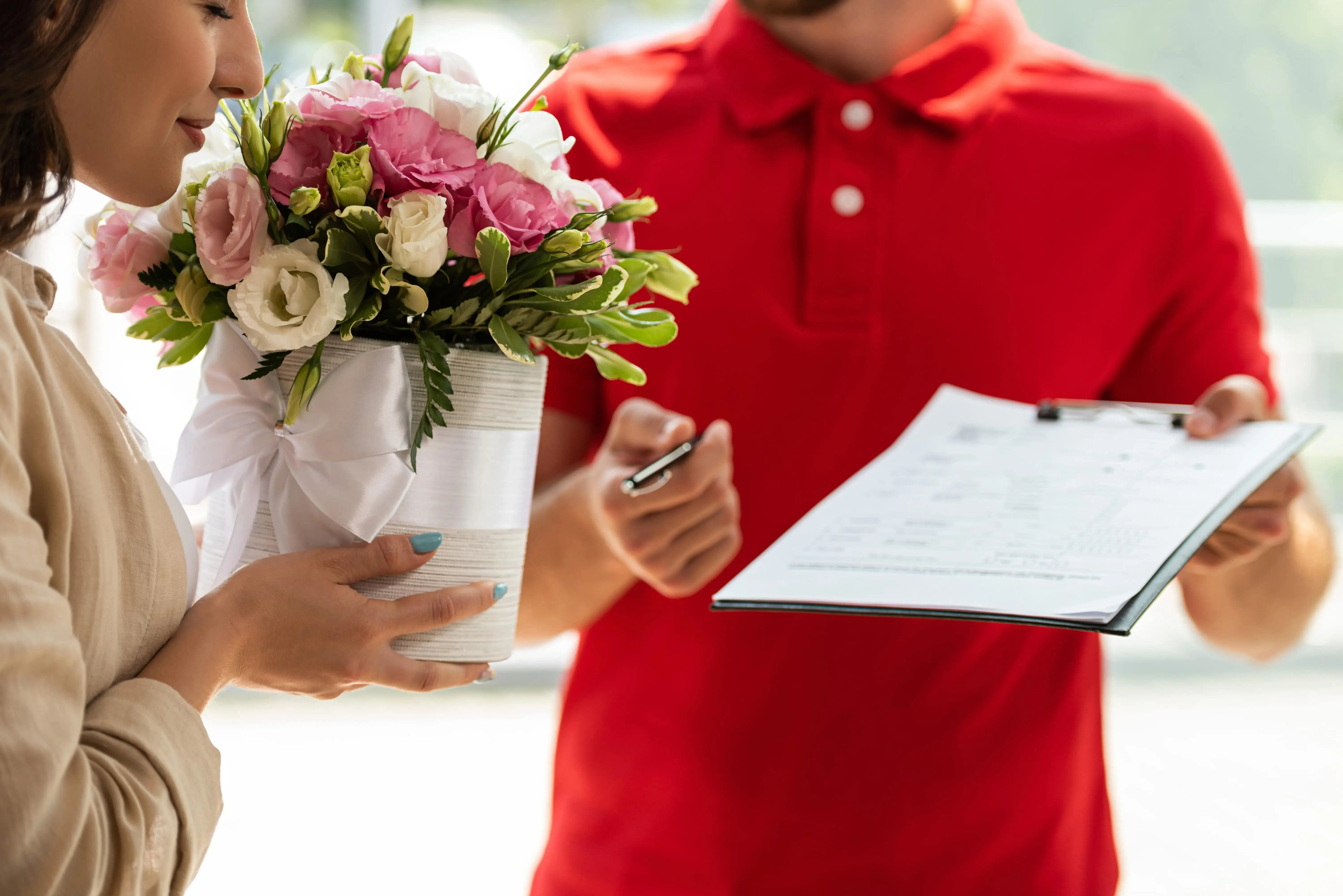 Woman receiving bouquet, signing for flowers.