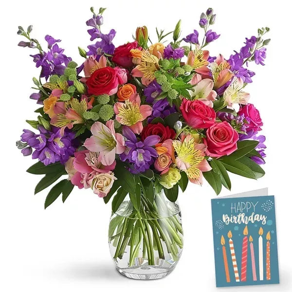 Colorful bouquet of mixed flowers in a glass vase with a 'Happy Birthday' card.