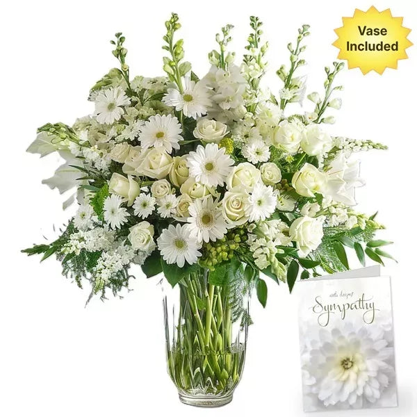 A large bouquet of white flowers in a vase with a sympathy card.